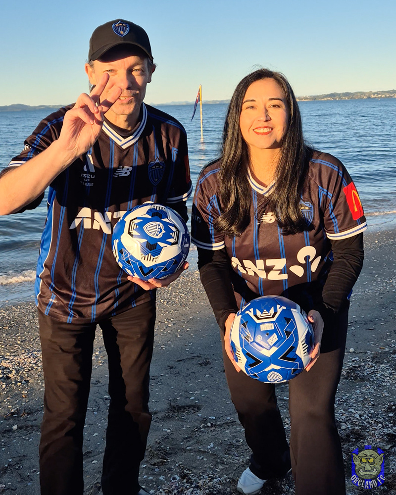 Rob and Ange from Orcland FC at the beach with two signed Auckland FC Footballs to giveaway.